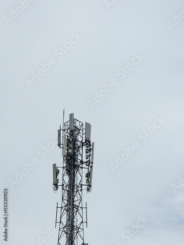 Mobile network tower structure with multiple antenna arrays captured from below on a dull sky day photo
