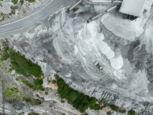 Aerial view of granite and limestone crushing plant with dump trucks and excavators processing raw stone into construction aggregates for concrete and infrastructure development. Stone mill factory.