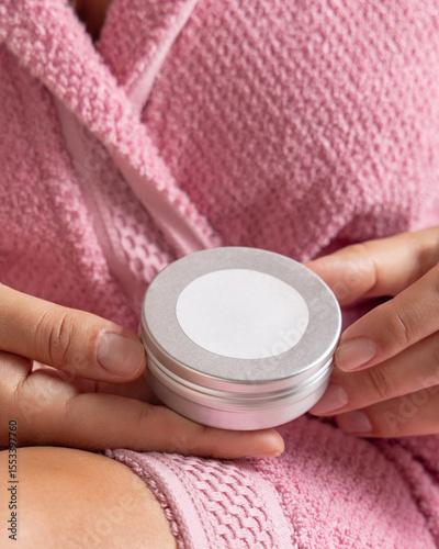 Woman in pink bathrobe holding body butter jar with a label in hands, Closeup, cosmetic mockup