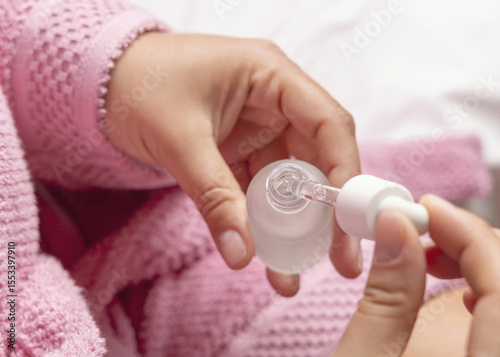Closeup of young woman in pink bathrobe opening dropper bottle top view, cosmetic mockup