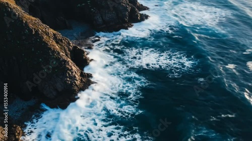 Ocean waves crashing on rocky shore from aerial perspective with foamy water, seamless looping 4k time-lapse animation video background. Nature concept
