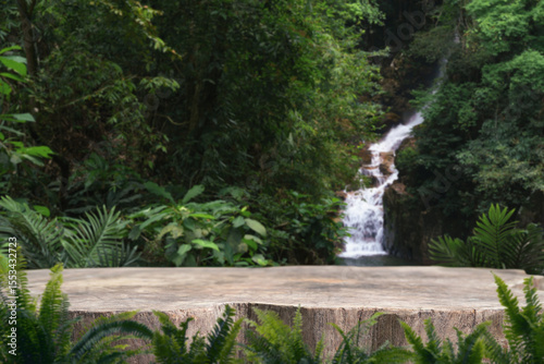 wood stump table top podium with outdoor waterfall tropical forest nature background landscape.Natural water mineral product present placement pedestal wooden stand display.jungle paradise concept.