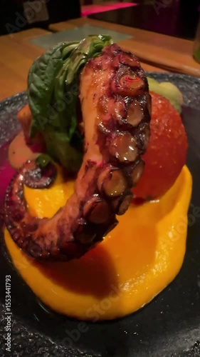 Octopus on a carrot bed with baked tomato and herbs.