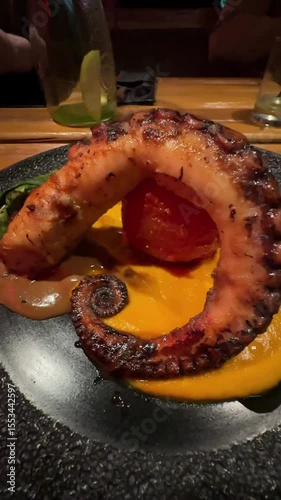 Octopus on a carrot bed with baked tomato and herbs.