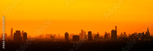 Evening panoramic view of city silhouettes of buildings and skyscrapers, the dying sky after sunset and amazing orange color clouds.