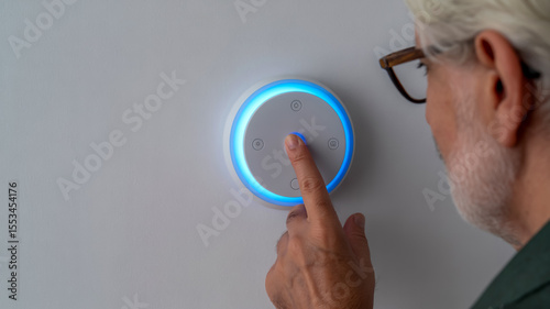 Finger pressing a smart home control button on the wall with blue light