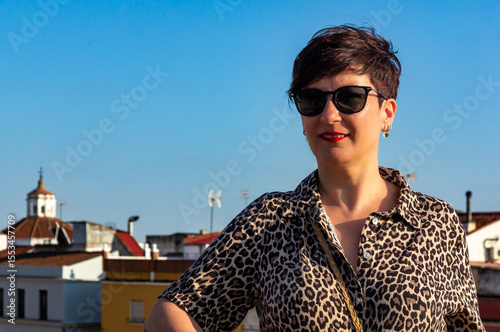 Positive Energy: Mature Woman Enjoying the Sun with Urban Backdrop and Blue Sky.