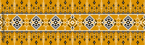 Traditional textile pattern featuring geometric shapes and symmetrical designs in mustard yellow, white, and black tones.