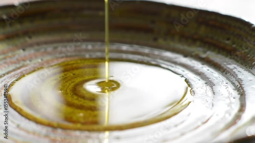 Close-Up of Olive Oil Pouring in Thin Stream onto Ceramic Plate – Cinematic Lighting
