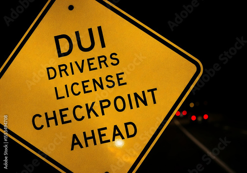 DUI Checkpoint Warning Sign at Night with Reflective Surface and Car Lights in Background