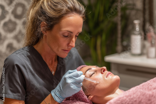 Cosmetologist gently applying serum to client's face in a tranquil spa setting