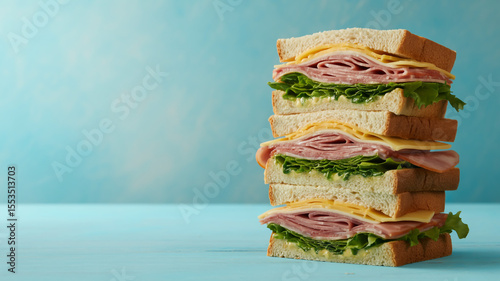 A professional food photography shot of a tall club sandwich stacked four layers high against a light turquoise background