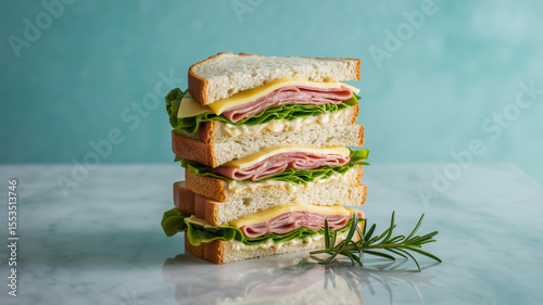 A professional food photography shot of a tall club sandwich stacked four layers high against a light turquoise background
