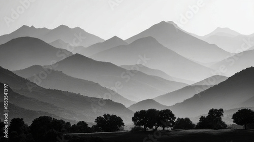 Misty mountain valley with layered ridges and soft light in grayscale landscape