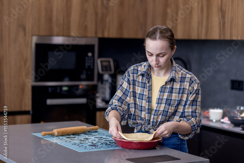 Woman skillfully rolls out dough, perfectly showcasing her culinary expertise in a kitchen