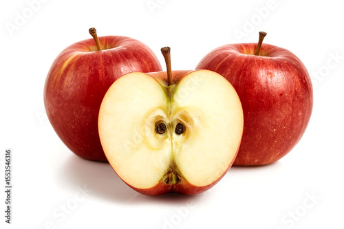 A studio shot features two whole red apples and one apple cut in half showcasing its crisp white flesh core and brown seeds against a clean white background