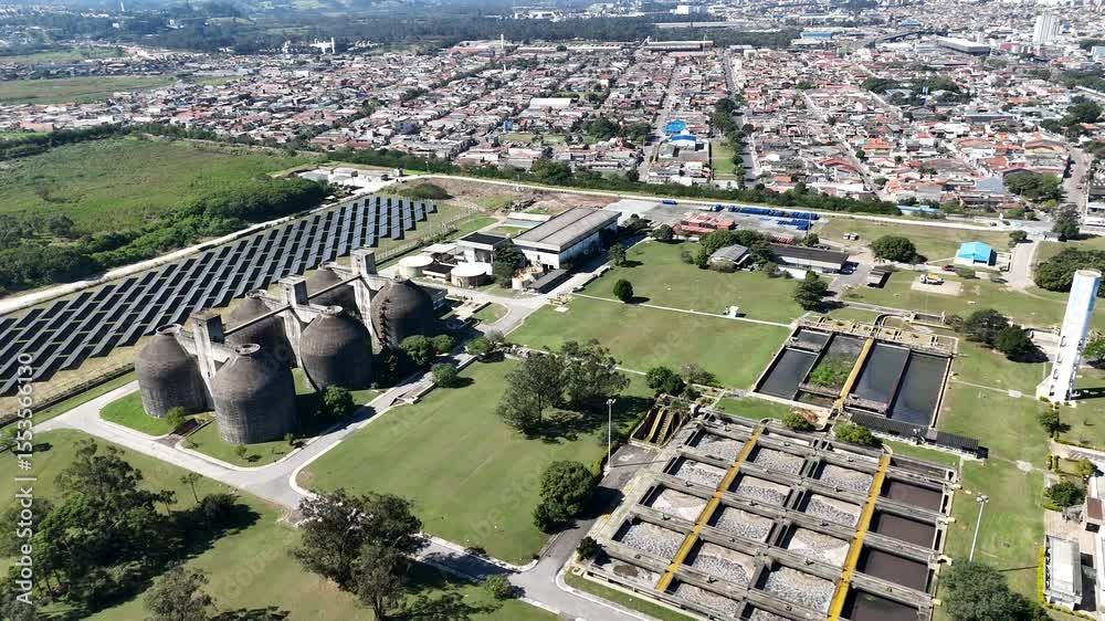 Visão aérea ampla de instalações de saneamento com estruturas de tratamento e canais visíveis com vista para os decantadores, tratamento lodo ativado e sistema industrial