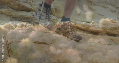 Hiker planting trekking pole tip and shifting weight over sandstone ledge for desert exploration
