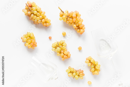 Two glasses of wine with ripe yellow grapes on white background, top view