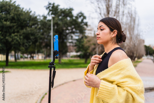 Vászonkép Young woman attaching her lavalier microphone while preparing to record a video
