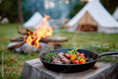 Wallpaper Mural Deliciously cooked steak and vegetable in pan on log with bonfire and camping tents in background, peaceful outdoor dinner scene Torontodigital.ca