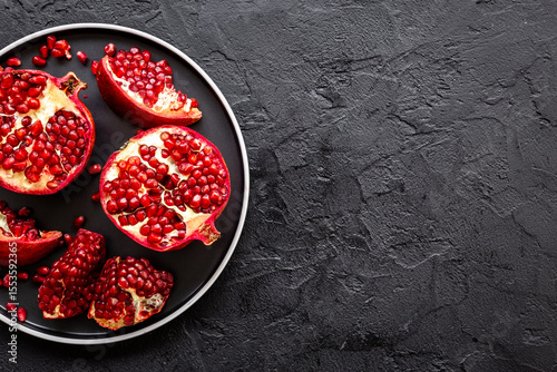 Top view of fresh ripe pomegranate and pieces on plate for eating, top view.