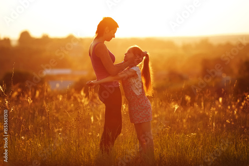 Happy mother and daughter in the field on a summer evening.