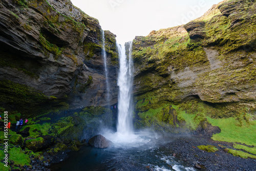 Visitors marvel at the stunning Kvernufoss waterfall, cascading gracefully from rocky cliffs