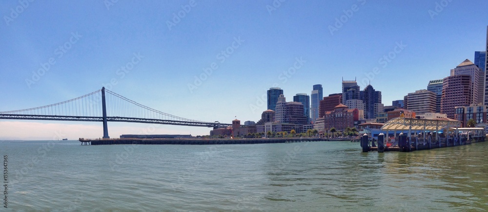 Obraz premium Panoramic view of a city skyline and bridge over water in daylight