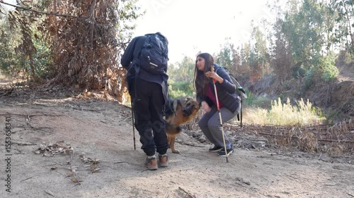 Latin American hikers petting their german shepherd dog during a trekking excursion