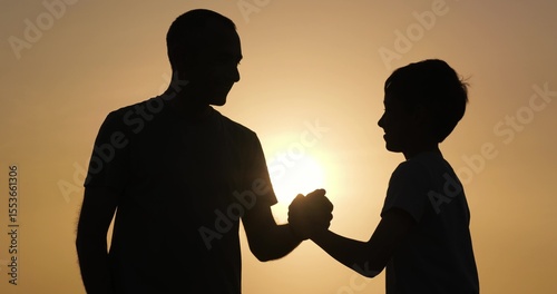 Dad and son share handshake outdoors. dad and son connect through meaningful handshake, expressing trust. Dad and son handshake shows support, family bond, encouragement, and respect.