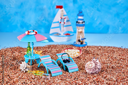 postcard with an image of a summer relaxation corner on the sea beach with sun loungers, a stand with an umbrella and a swing on a blue background with a sailboat and a lighthouse
