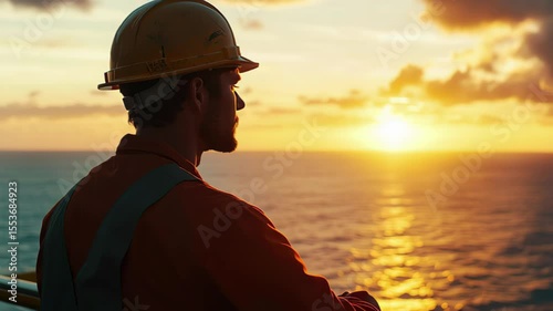 Oil worker watches as the sun sets over the ocean while taking a break from work offshore, Oil worker looking out over the ocean at sunset