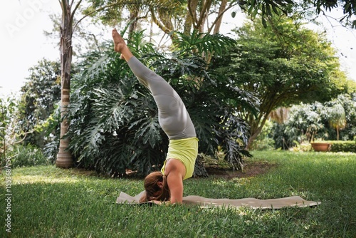 Latin woman practicing supported headstand yoga pose in a garden