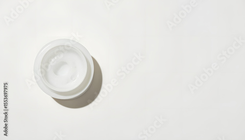 White cosmetic cream jar placed on a smooth surface with soft shadows, showcasing the product's texture and inviting potential buyers to explore skincare options and beauty solutions