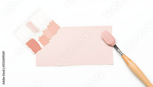Paint swatches in soft pink tones are displayed alongside a paintbrush on a blank canvas, showcasing color selection for interior design projects and creative applications