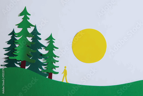 Paper cutout illustration of person walking near forest at daytime