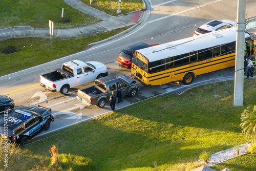 First responders responding to school bus and car accident site on American street. Emergency services helping victims of vehicle crash on road in USA