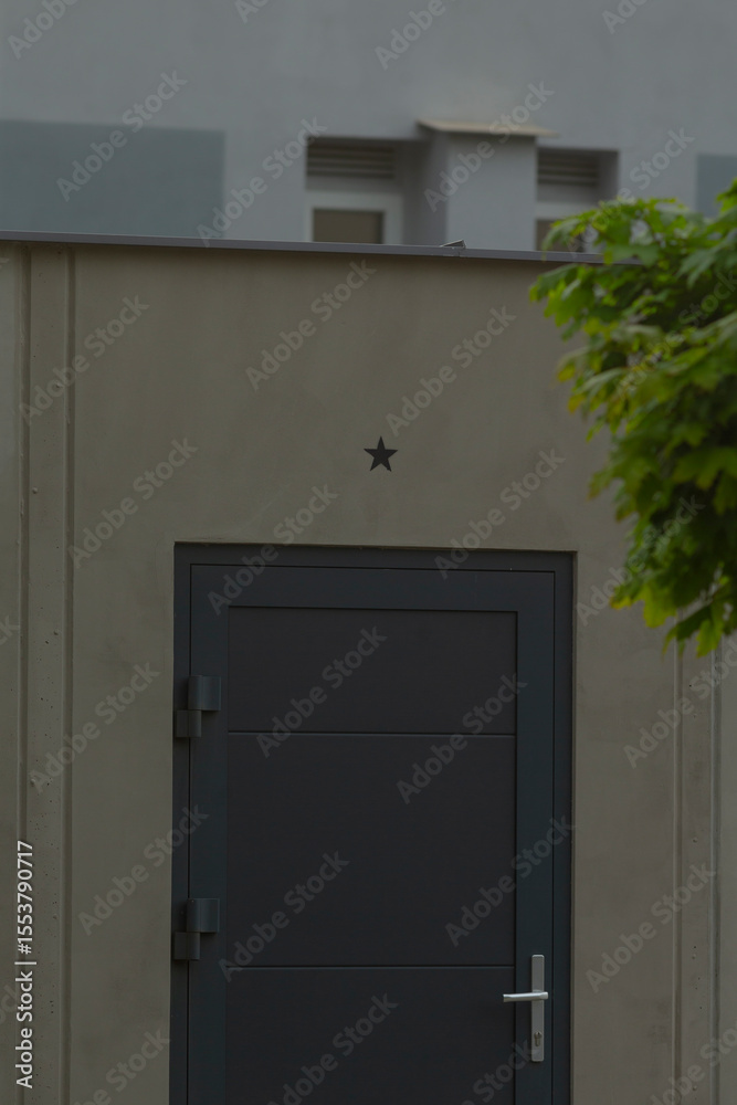 Fototapeta premium On the side of a building, there is a striking black door adorned with a decorative star, making it stand out against the structure
