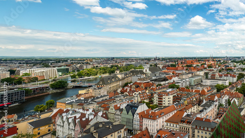 A panoramic overhead view showcasing the historic downtown area, filled with vibrant buildings, churches, and architectural landmarks under a clear blue sky, Wroclaw, Poland