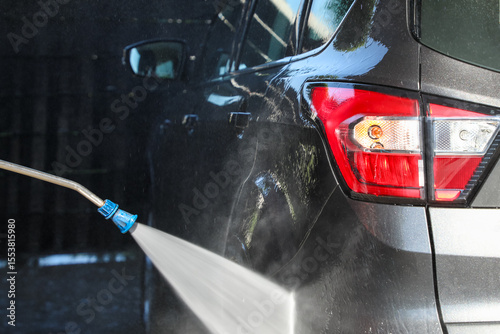 фотографія Using a pressure washer at a car wash on a sunny day, washing a car at a self-se
