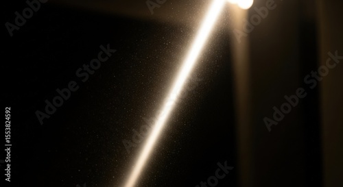Bright light beam with floating dust particles on dark black background. Abstract atmospheric illumination for spiritual and funeral concepts.