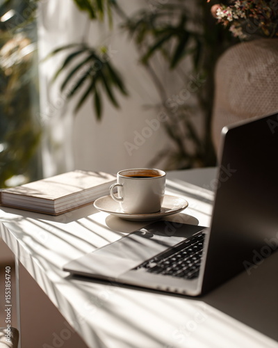 modern laptop partially closed on desk with coffee cup