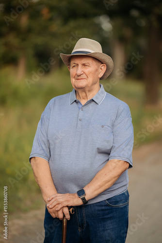 Grandfather in a hat. Portrait of a very old Caucasian man. Portrait: elderly, lonely, elderly, with many wrinkles on his face. Close-up of a thoughtful old man standing alone outdoors.