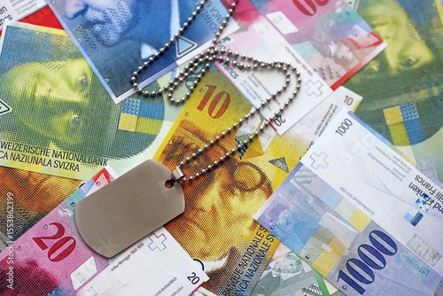Swiss franc banknotes and military token. The current francs money bills and dogtags lies on table