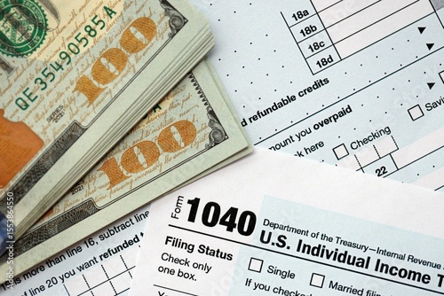 Hundred dollar bills and 1040 individual income tax return form blank close up photo