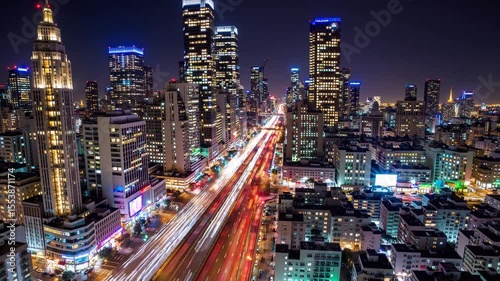 Vibrant night cityscape with illuminated skyscrapers and light trails from traffic in a modern urban downtown.