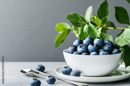 Fresh Blueberries With Green Leaves Arranged on a Light Gray Surface.