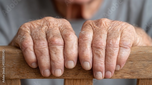 Close-up of aged hands resting on wooden surface, showcasing intricate details and a sense of history.