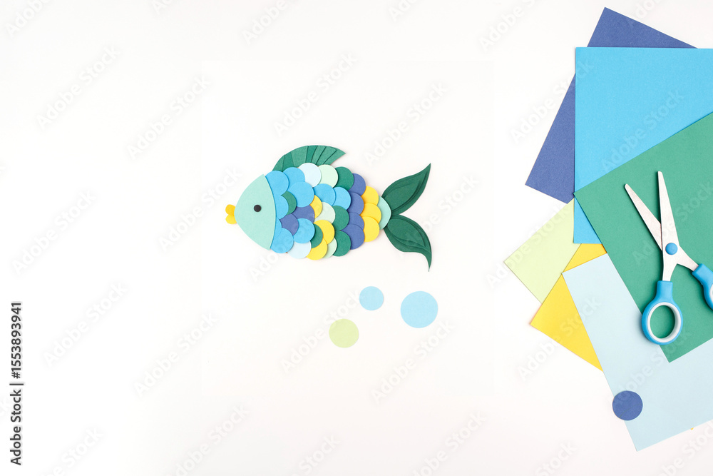Fototapeta premium Colorful fish paper craft with scissors and paper circles for creative learning visuals, preschool activities, DIY tutorials, kids craft kits, toy branding, and educational content platforms.